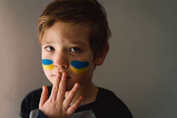 Ritratto di un ragazzo ucraino con un volto dipinto con i colori della bandiera ucraina. - Foto, immagini