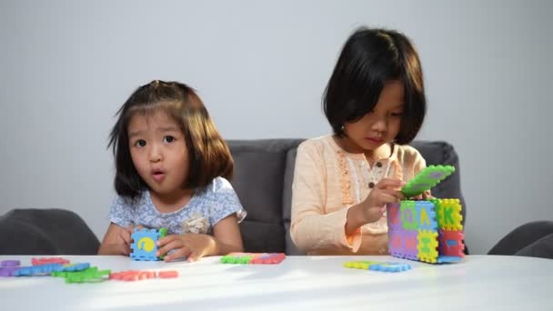 かわいいアジアの妹と同じ妊娠中の兄弟がカラフルなおもちゃで遊んでいますABCジグソーパズル、子供たちは脳の発達と想像力のための教育玩具で遊ぶ。子供の発達の概念の創造的な遊び - 映像、動画