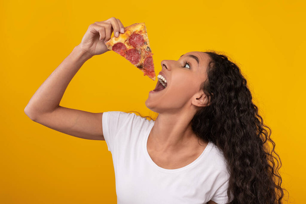 Happy Latin Lady sosteniendo rebanada de pizza en el estudio - Foto, Imagen