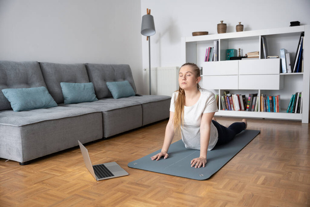 Young woman taking yoga virtual course at home. - Photo, Image