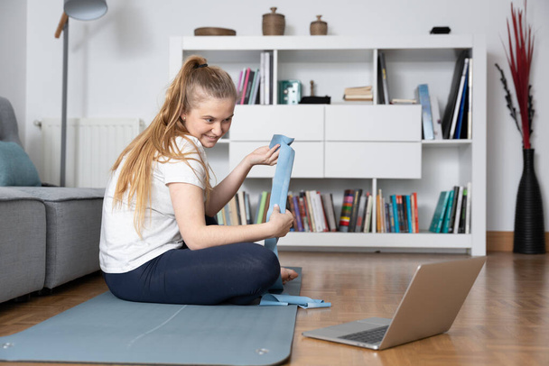 Pilates teacher showing a rubber band to students at virtual class at home. - Photo, Image