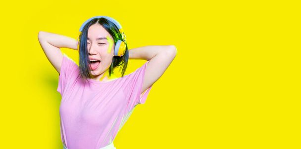 Young asiatic woman listening music laughing isolated background - copyspace cropped banner - Fotó, kép