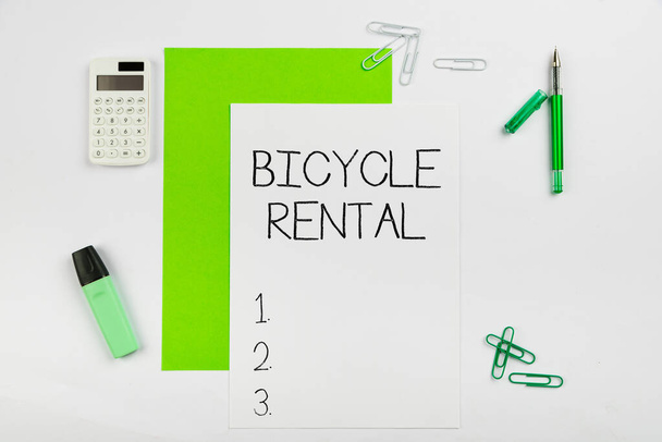 Hand writing sign Bicycle Rental. Business approach a business which rents out bikes to tourists or travellers Multiple Assorted Collection Office Stationery Photo Placed Over Table - Photo, Image