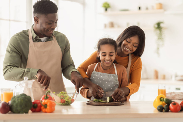 Afro-Amerikaanse familie koken snijden groenten maken salade in de keuken - Foto, afbeelding