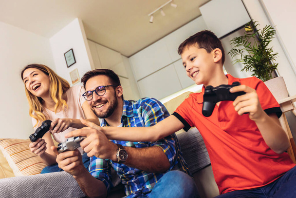 Портрет щасливої сім'ї, що проводить вільний час, відвідуючи змагання з відеоігор, що виграють у світлому сучасному будинку
. - Фото, зображення