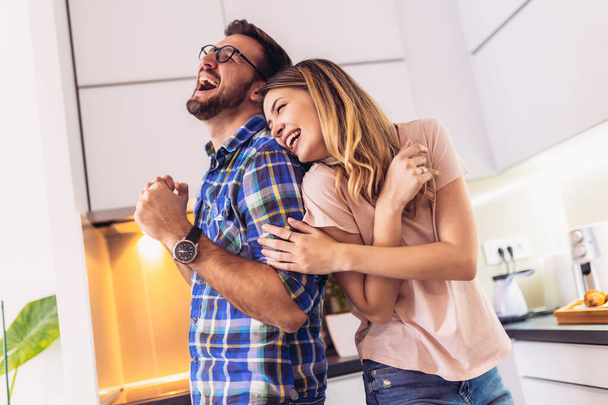 Молода пара в сучасній кухні, танцює і сміється, щаслива молода дружина і чоловік переходять до улюбленої музики
. - Фото, зображення