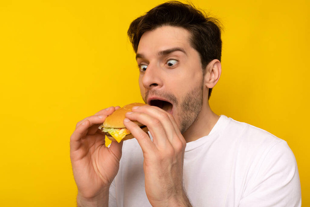 Funny Young Guy Holding Burger At Studio - Foto, Imagen