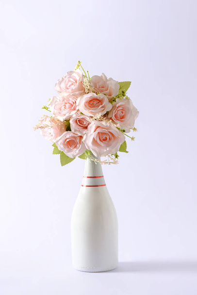 Букет свіжих рожевих квітів у білій пляшці шампанського над зеленим кольором з копіювальним простором на День святого Валентина. - Фото, зображення