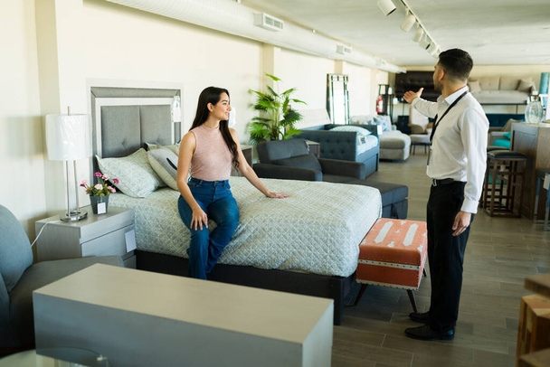 Bella giovane donna che parla con un rappresentante di vendita maschile per acquistare nuova camera da letto mobili - Foto, immagini