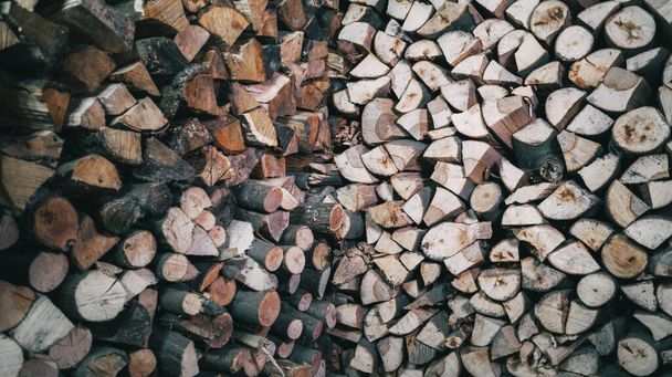 Background of a pile of wooden firewood neatly placed on the wall - Foto, afbeelding