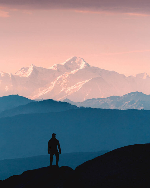 silhouette of a man with a backpack on the top of the mountain - Photo, Image