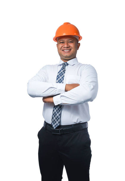 Jonge ingenieur of architect staat met armen gekruist glimlachend gelukkig geïsoleerd op witte achtergrond met clipping pad - Foto, afbeelding