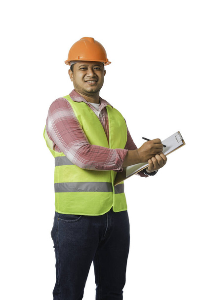 Porträt eines gut aussehenden Chefingenieurs mit hartem Hut. trägt einen reflektierenden Tiger und macht sich Notizen. isoliert auf weißem Hintergrund. - Foto, Bild