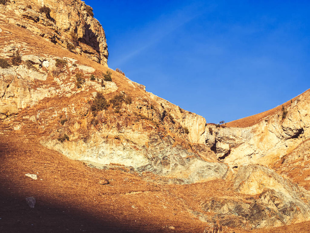 Jyrkkä syksy kivinen vuoret Kaukasuksen kuiva kultainen ruoho palaa auringon alla sininen taivas - Valokuva, kuva
