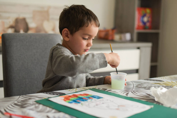 young caucasian boy doing painting at home with pleasure - Photo, Image
