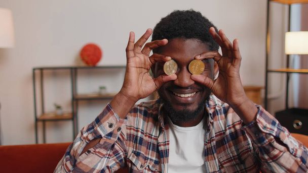 Hombre freelancer celebración de dos monedas de oro BTC en casa, desarrollador exitoso programador stock trader - Foto, imagen