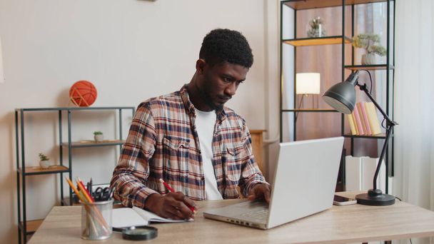 Hombre joven usando ordenador portátil sentado en la mesa de trabajo, compras en línea de la oficina en casa - Foto, Imagen