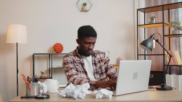 Vihainen raivoissaan mies työskentelee kotona toimistossa rypistyneellä paperilla, jolla on hermoromahdus töissä - Valokuva, kuva