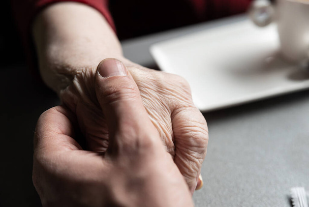 Close up of the hands of a 43 year old white man holding the hands of his 83 year old mother, Tienen - Fotoğraf, Görsel