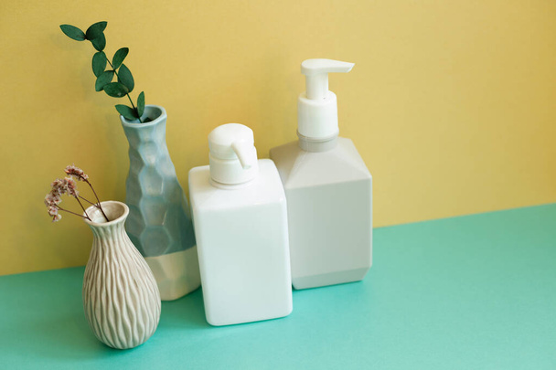 Huidzeep, shampoo, conditioner fles op groene tafel. gele muur achtergrond. Badkamer interieur - Foto, afbeelding