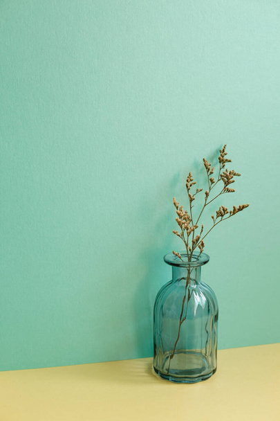 Florero de flores secas sobre mesa amarilla. fondo de pared verde. interior del hogar - Foto, imagen