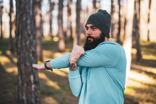 Man with beard enjoys exercising in nature. - Foto, afbeelding