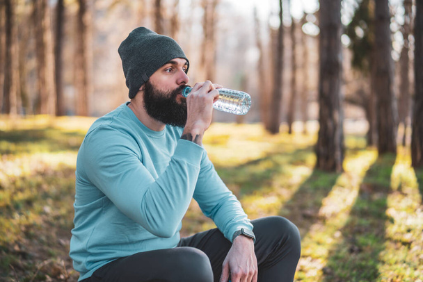 Man resting  after exercise and drinking water in the nature. - Fotografie, Obrázek