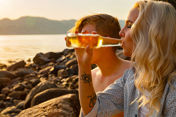 Jeune femme buvant de la bière par petit ami à la plage - Photo, image