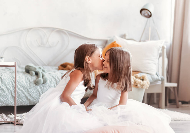 two little girls in white  dresses  in a bright studio have joj  - Fotoğraf, Görsel