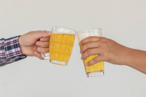 Eine Gruppe enger Freunde genießt eine Party und hebt fröhlich ihre Biergläser, bevor sie ein Bier aus einem Glas in der Hand trinken. Party-Ideen nach geschäftlichem Erfolg - Foto, Bild