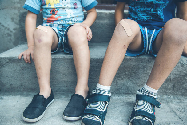 two boys injured leg sitting in street - Fotografie, Obrázek