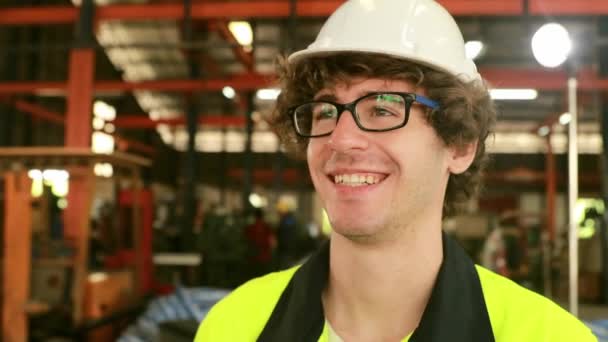 Close up face headshot: Retrato de jovem profissional feliz engenheiro da indústria pesada trabalhador vestindo capacete de segurança e óculos de segurança trabalhador industrial feliz olhando para cam - Filmagem, Vídeo