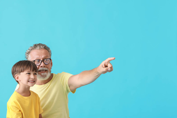 Mały chłopiec i jego dziadek wskazujący na coś na niebieskim tle - Zdjęcie, obraz