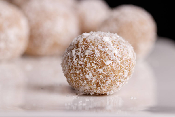 Belos doces com coco em uma placa branca em um fundo preto close-up - Foto, Imagem
