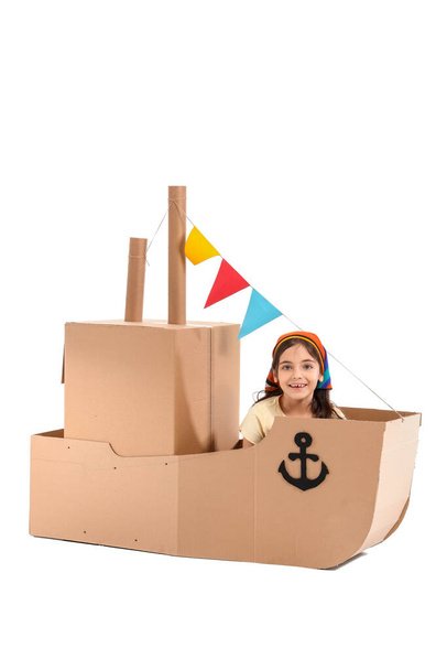 Divertente bambina che gioca con la nave di cartone su sfondo bianco - Foto, immagini