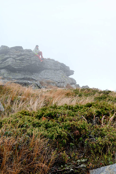 El turista se encuentra en una roca cerca del Monte Petros, ropa brillante para los turistas. - Foto, imagen