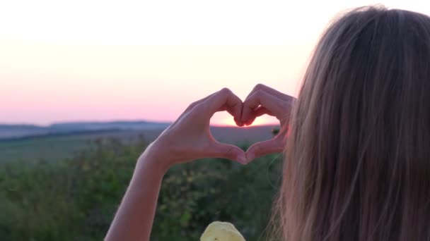 Toon hand gebaren hart op roze zonsondergang achtergrond, liefde en gezondheid concept - Video
