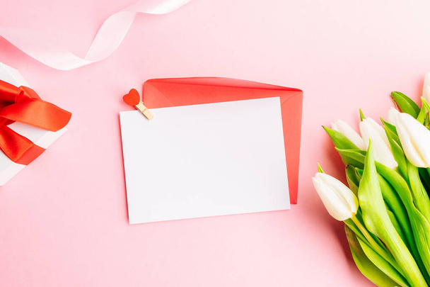Cadeau de la fête des mères. Printemps fleur de tulipe blanche, cadeau avec ruban rouge sur fond plat rose. Valentines, anniversaire, concept de femme ou jour de mariage - Photo, image