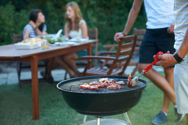 De perfecte zomerlunch. Jonge jongens barbecueën vlees op de grill buiten - Lifestyle. - Foto, afbeelding