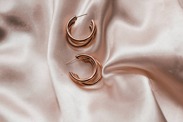 Gold jewelry earrings made of gold on the background of silk. - Photo, Image