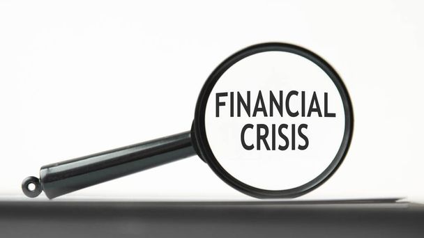 Finanzkrise ein Vergrößerungsglas auf das Wort Finanzkrise, ein Geschäftskonzept. Lupe auf weißem Hintergrund - Foto, Bild