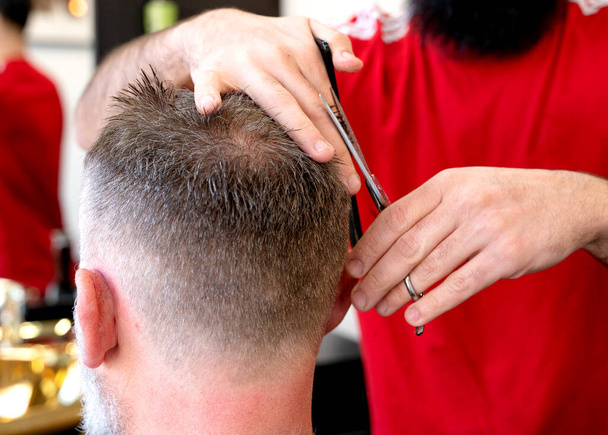Парикмахерская обрезка и резка бородатый человек с бритвой машины в парикмахерской. Процесс прически. - Фото, изображение