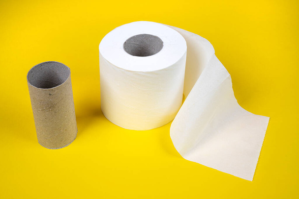 one whole and one finished toilet paper roll on a yellow background - Fotografie, Obrázek