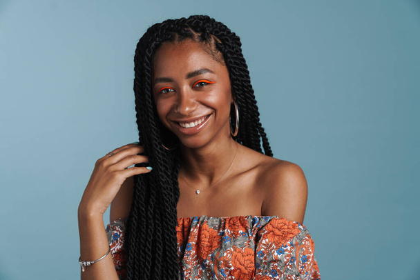 Young black woman with makeup smiling and looking at camera isolated over blue background - Photo, Image