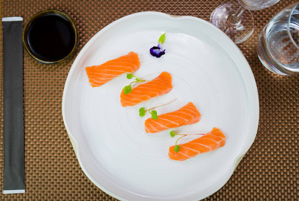 Delicious premium salmon nigiri on handmade white plate decorated with edible flower. - Fotoğraf, Görsel