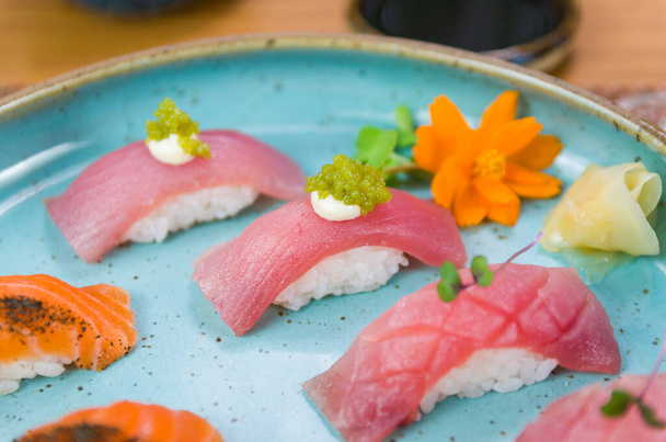 Assorted premium tuna and salmon nigiri sushi on a beautifully decorated plate. - Fotó, kép