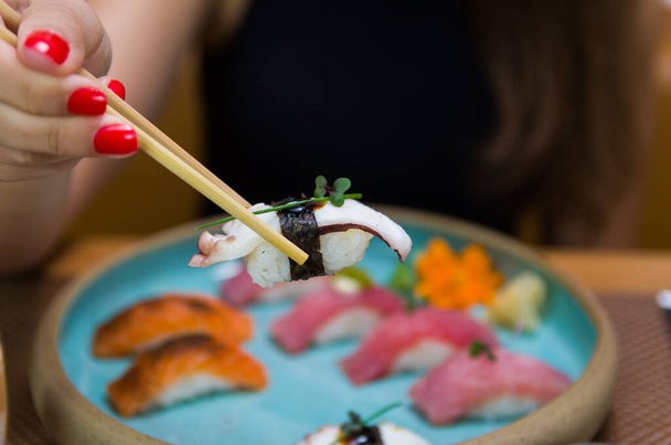 Woman eating delicious sushi, closeup on chopsticks - Foto, afbeelding