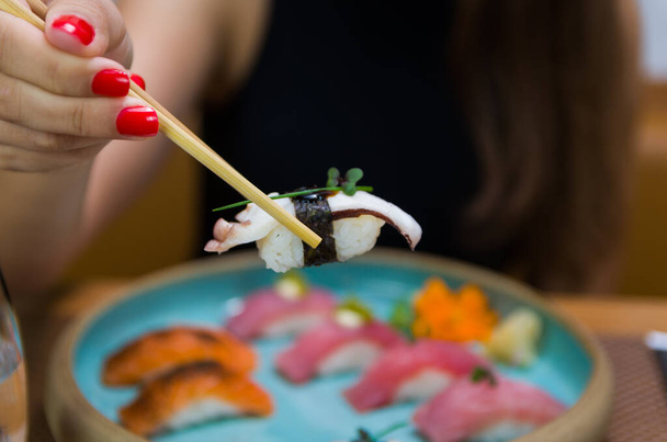 Woman eating delicious sushi, closeup on chopsticks - Foto, Bild