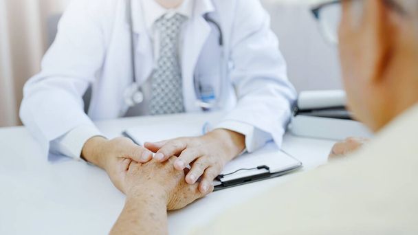 Hand of doctor comforting patient at consulting room. Doctor and patient are discussing consultation about symptom problem diagnosis of disease - Photo, Image
