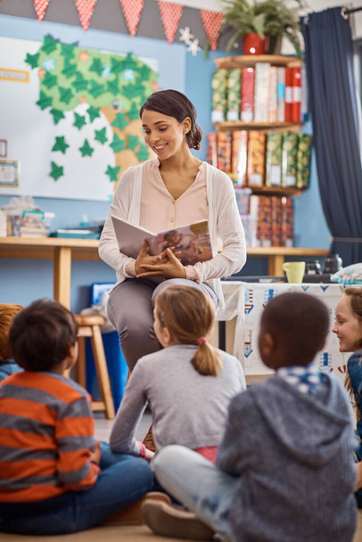 La lectura abre aún más su imaginación. Fotografía de un profesor leyendo a un grupo de niños de primaria en clase. - Foto, imagen